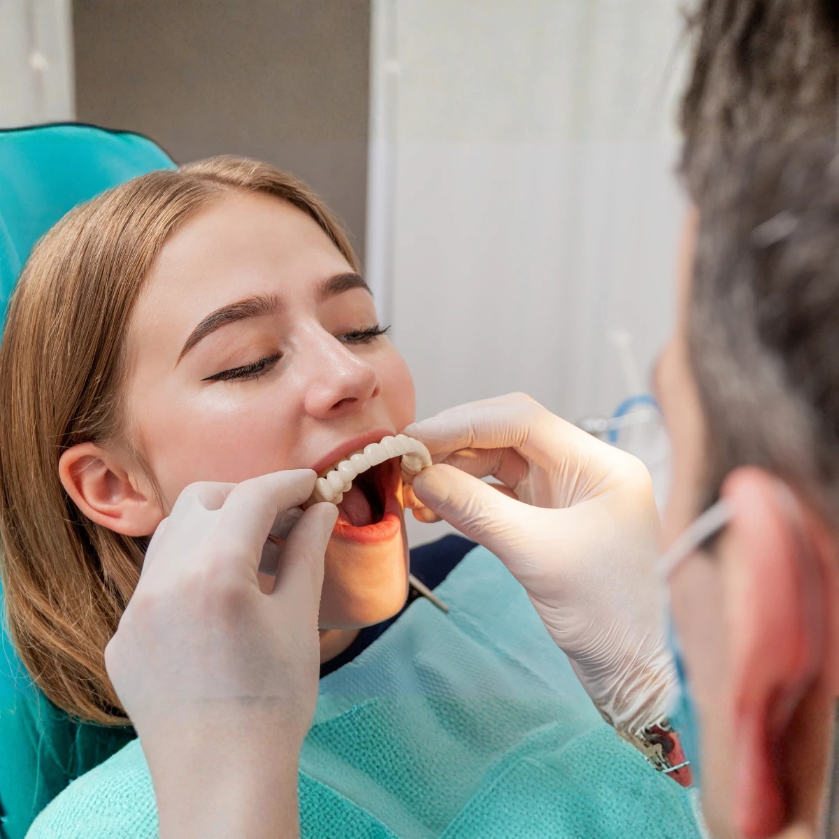 Odontólogo colocando una prótesis dental fija a una paciente
